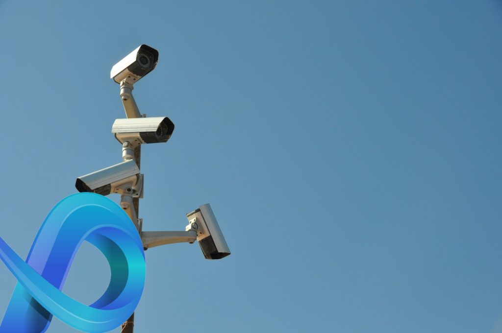 Groupe de caméras de sécurité sur un poteau contre un ciel bleu clair, illustrant les avantages de combiner la vidéosurveillance avec l'IoT.