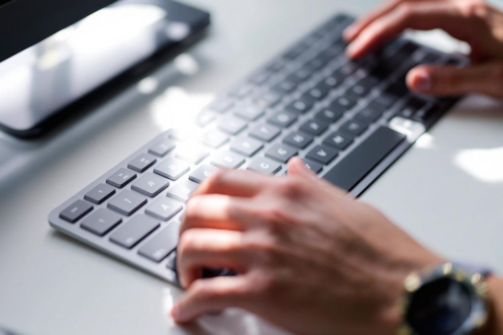 Gros plan sur des mains travaillant sur un clavier d'ordinateur